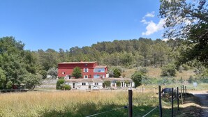 A red two-story house with a tiled roof, surrounded by a fenced field and trees. - La ferme de Manon les Lavandes in an 18th century farmhouse (MONTFERRAT)
