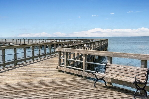A wooden pier extending into calm waters with a bench and railing.