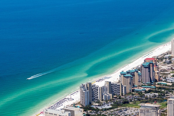 A coastal cityscape with high-rise hotels, a beach, and a clear blue sea.