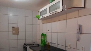 A kitchen with white cabinets, a black countertop, a microwave, and a green container. - Sky Tower (Fortaleza)