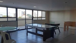 A room with a large window, a round table, and two rectangular tables with chairs. - Sky Tower (Fortaleza)