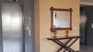 A hallway with a beige wall, a wooden console table, and a mirror. - Sky Tower (Fortaleza)