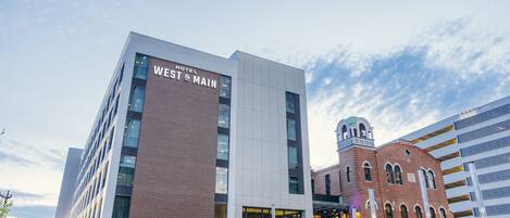 A modern hotel with a prominent sign reading "WEST MAIN HOTEL".