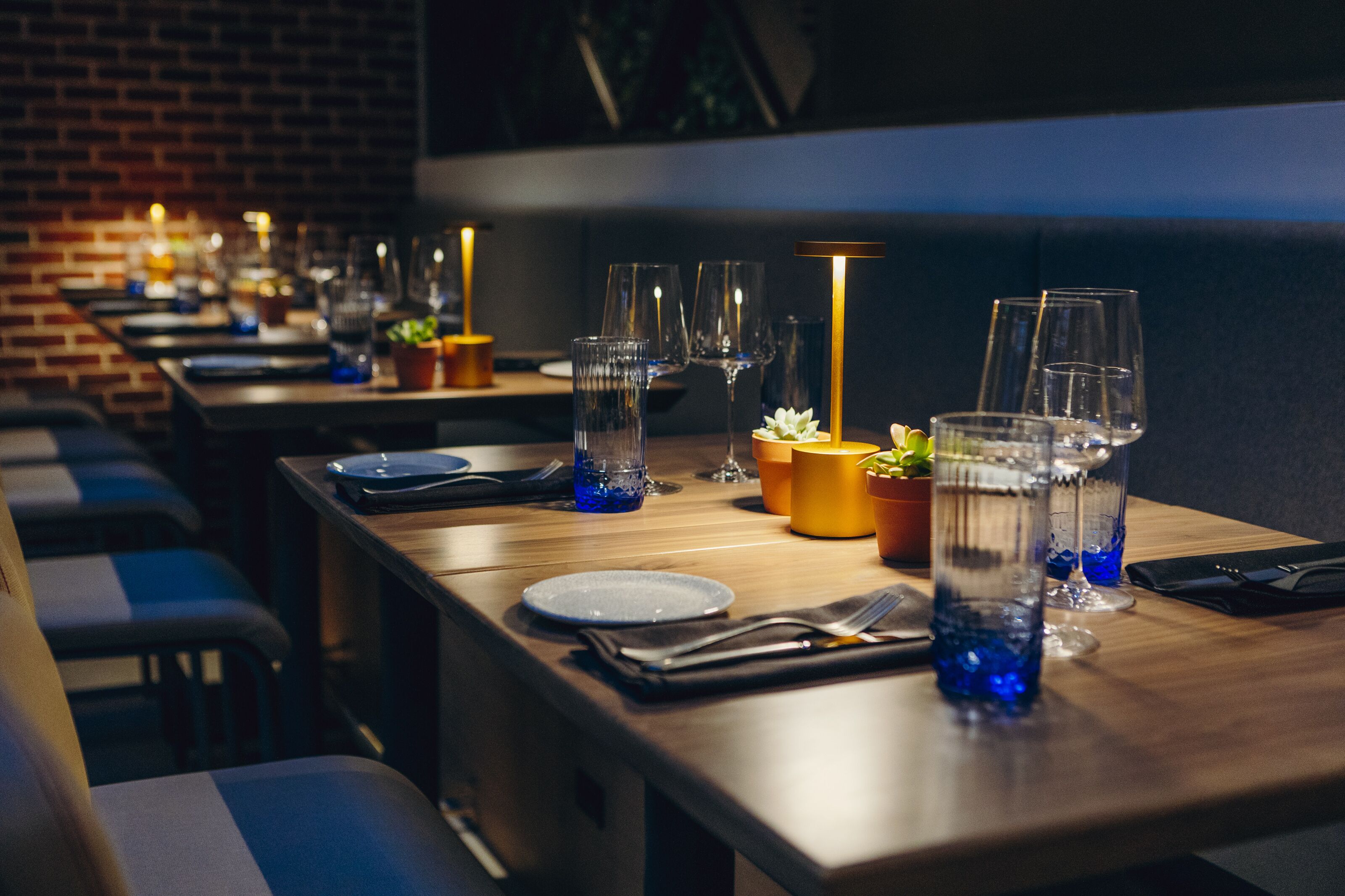A restaurant with long tables set for dining, each with plates, cutlery, and glasses.