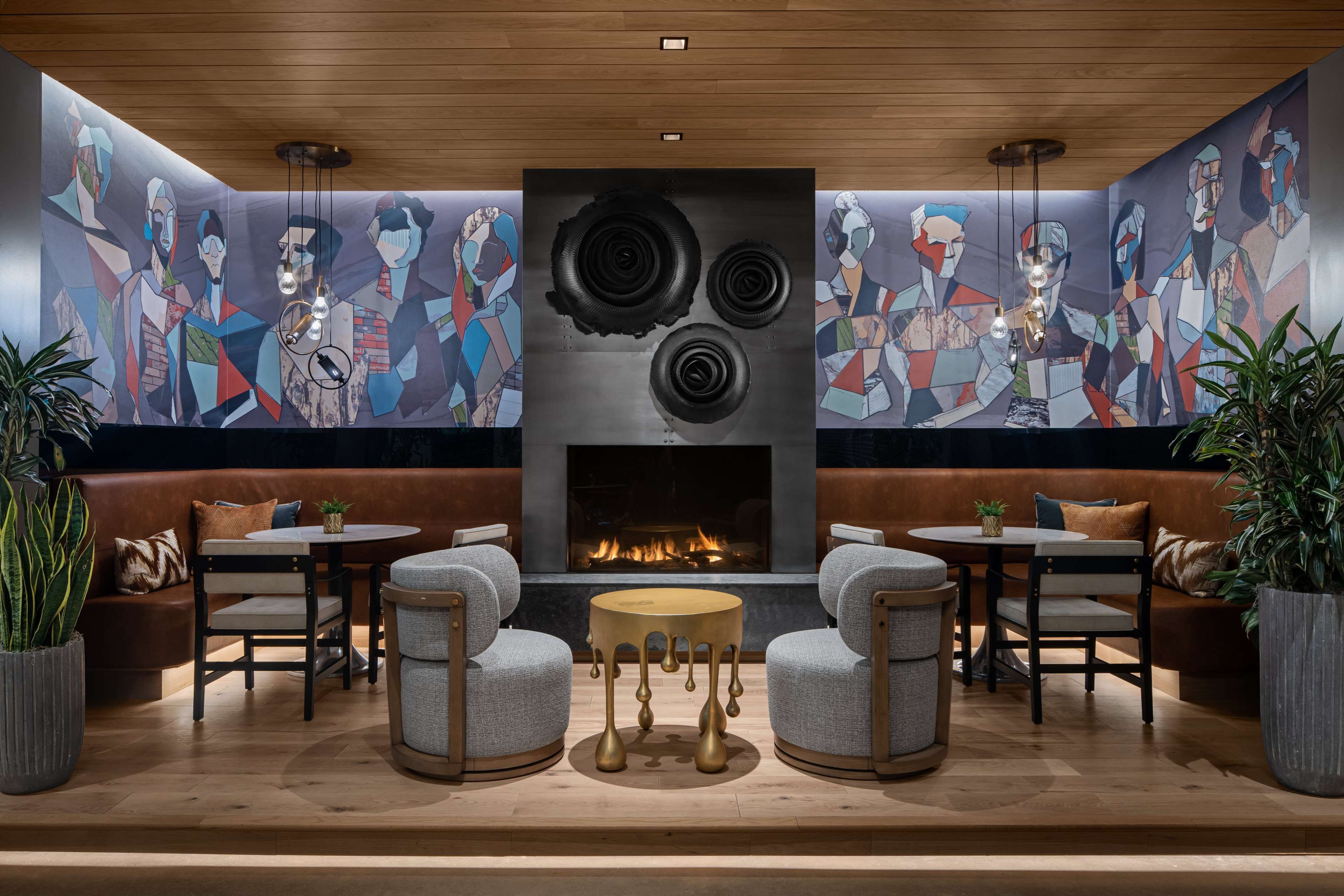 A modern lounge area with a fireplace, seating, and a geometric mural.