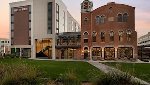Un hotel con un edificio moderno y una estructura tradicional de ladrillo, que cuenta con asientos al aire libre y una escalera que lleva al nivel superior.