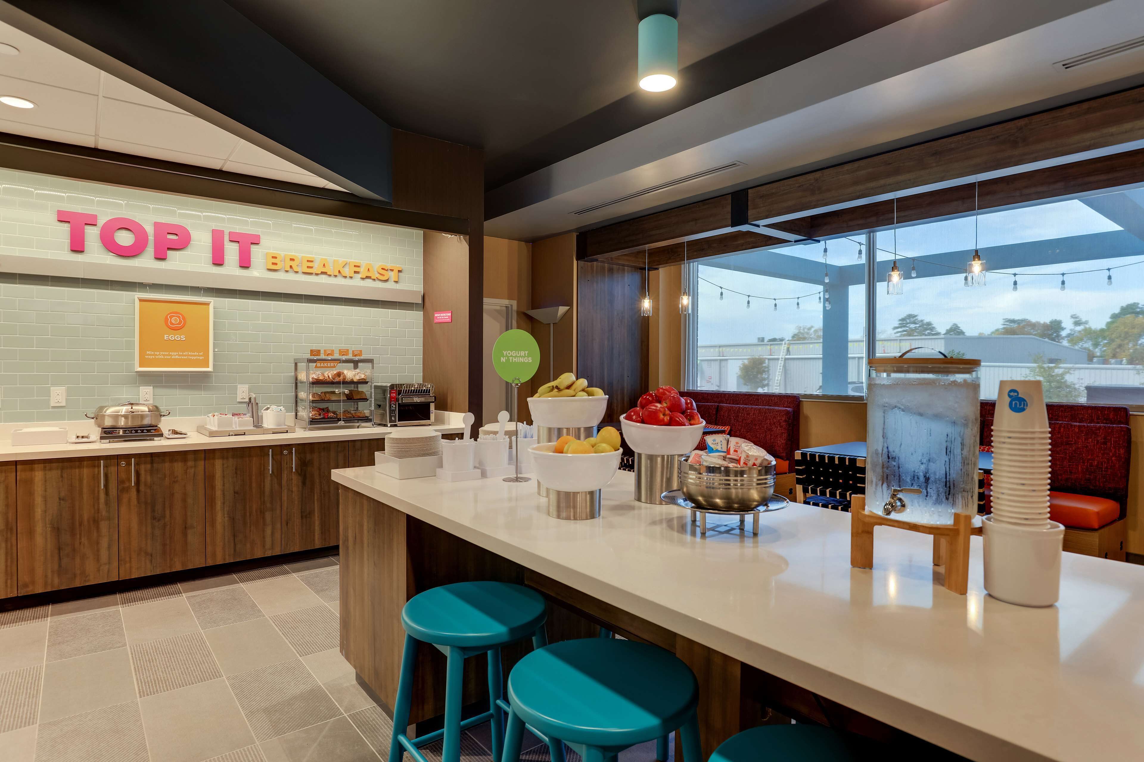A breakfast bar with a sign reading "TOP IT BREAKFAST," featuring a variety of food items and a yogurt display.