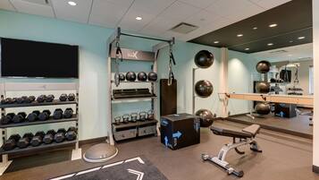A gym with weight racks, kettlebells, a rowing machine, and exercise balls.