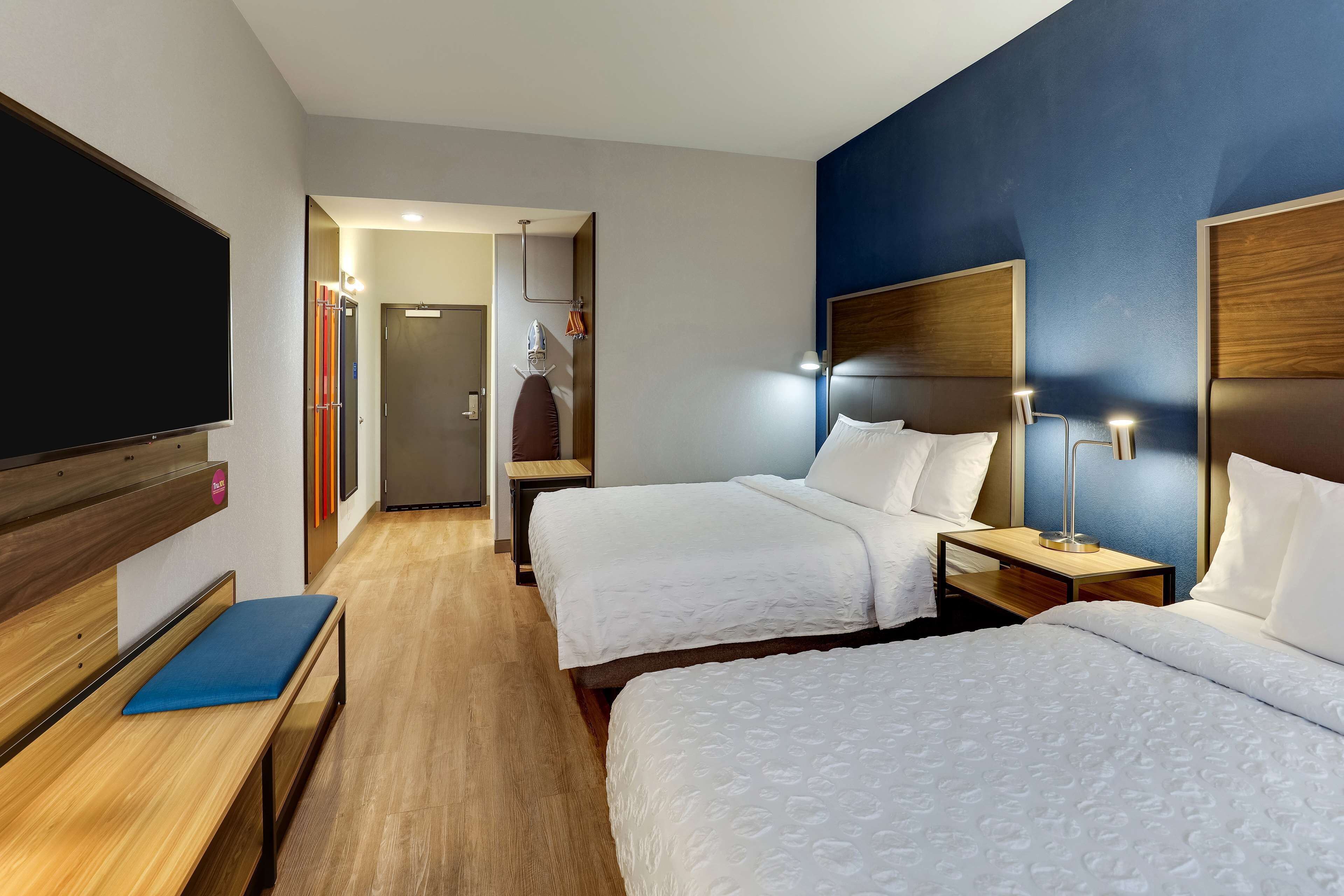 Een hotelkamer met twee bedden, een televisie, een bankje en een bureau.