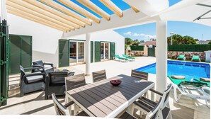 An outdoor patio area with a pool, lounge chairs, and a table with chairs.