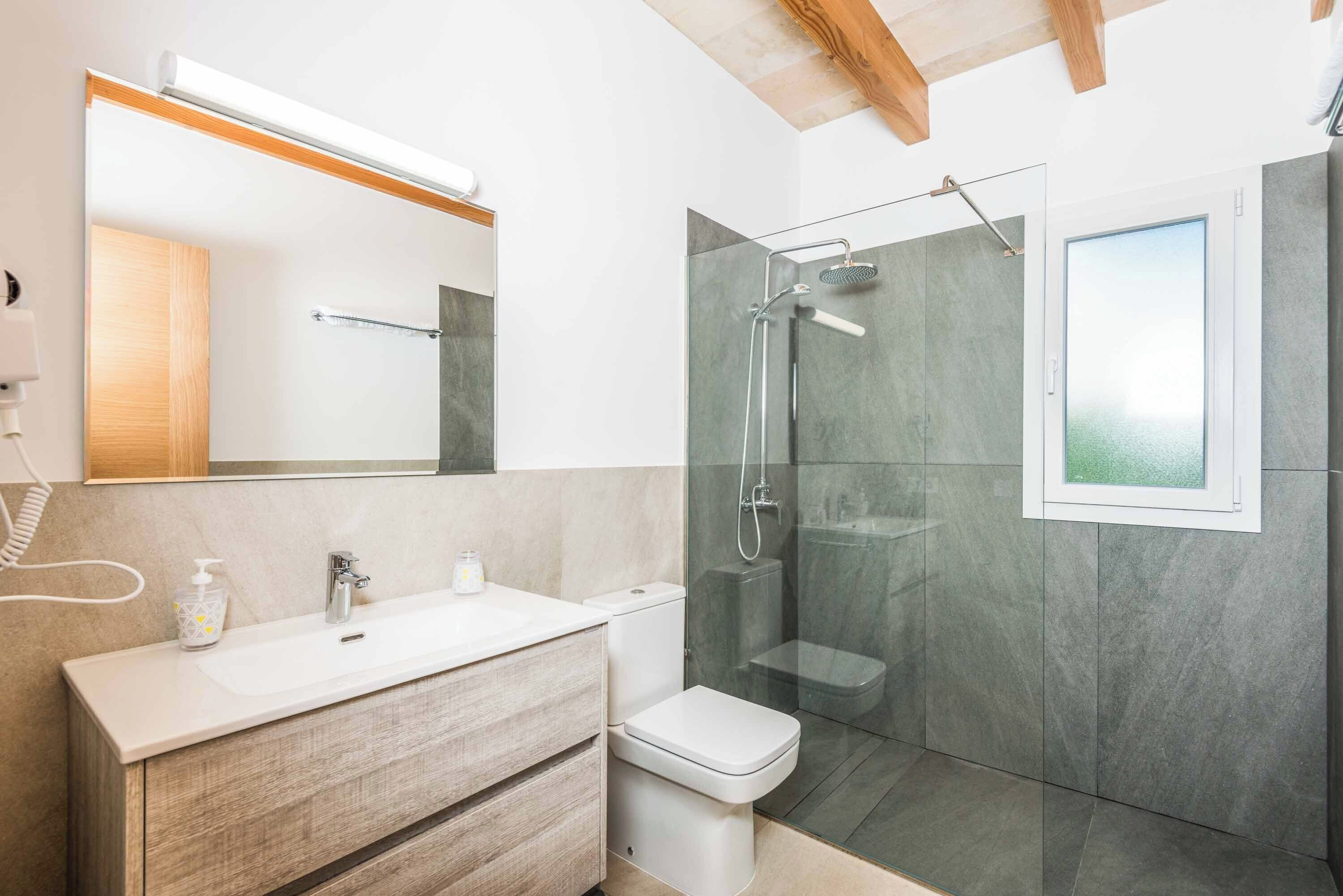 A modern bathroom with a wooden vanity, a glass shower enclosure, and a large mirror.