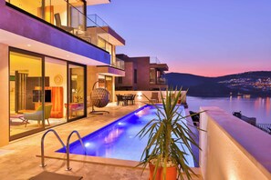 Een infinity pool, een verwarmd zwembad, ligstoelen bij het zwembad