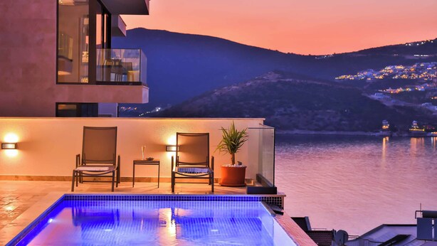 A modern pool area with a view of a hillside town at dusk. - Villa Bank Two - Three Bedroom Villa, Sleeps 8 (Kalkan)