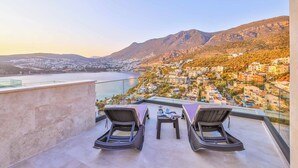 A rooftop terrace with two lounge chairs and a small table, overlooking a coastal town and mountains. - Villa Bank Two - Three Bedroom Villa, Sleeps 8 (Kalkan)