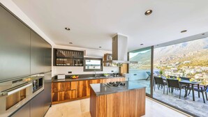 A modern kitchen with a central island, stainless steel appliances, and a view of a mountainous landscape. - Villa Bank Two - Three Bedroom Villa, Sleeps 8 (Kalkan)