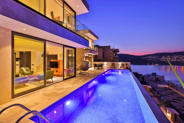 Een infinity pool, een verwarmd zwembad, ligstoelen bij het zwembad