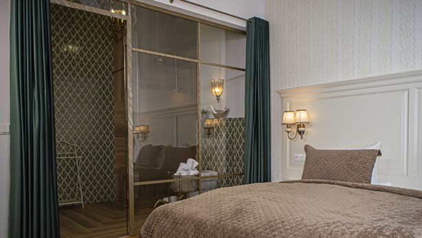 A hotel room with a large bed, a glass door leading to a balcony, and a wall-mounted lamp. - Palatul Brukenthal Avrig (Avrig)