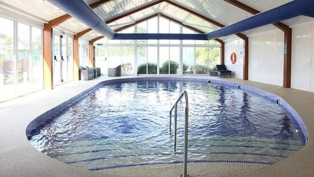 An indoor swimming pool with a clear roof structure, surrounded by glass walls and a tiled floor. - Luxury 2 Bedroom Holiday Home on Beachside Park (Par)
