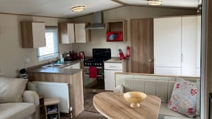 A compact RV interior with a kitchenette, a dining area, and a seating space. - Luxury 2 Bedroom Holiday Home on Beachside Park (Par)