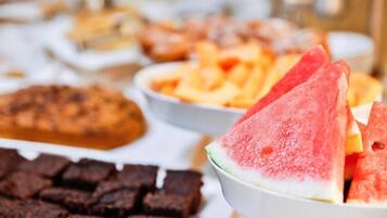 Un buffet proposant une variété de plats, notamment des tranches de pastèque, des brownies et d’autres desserts.