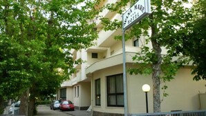 A hotel sign, a building with multiple windows, and parked cars along a tree-lined street. - Hotel Avana Mare (Rimini)