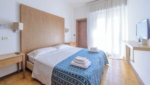 A hotel room with a bed, a desk, a TV, and a window with curtains. - Hotel Avana Mare (Rimini)