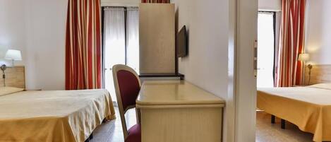 A hotel room with two beds, a desk, a chair, a TV, and curtains.