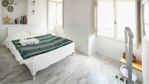 Una camera da letto con un letto, una finestra e uno scaffale con dei giocattoli.