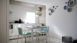 Una cucina moderna con mobili bianchi, un tavolo da pranzo con sedie e piatti decorativi appesi al muro.