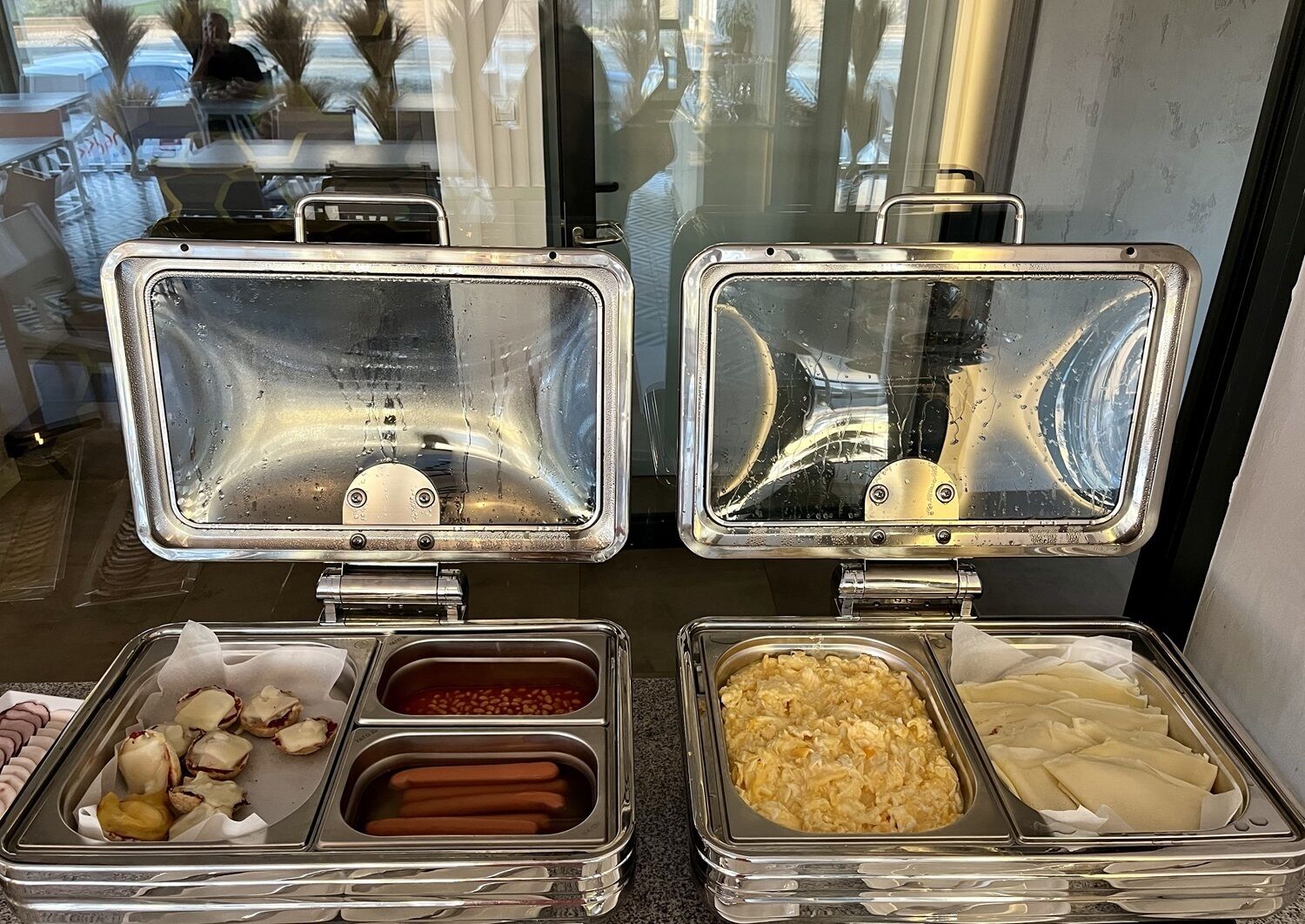 A buffet with various food items including hot dogs, macaroni, and other dishes.