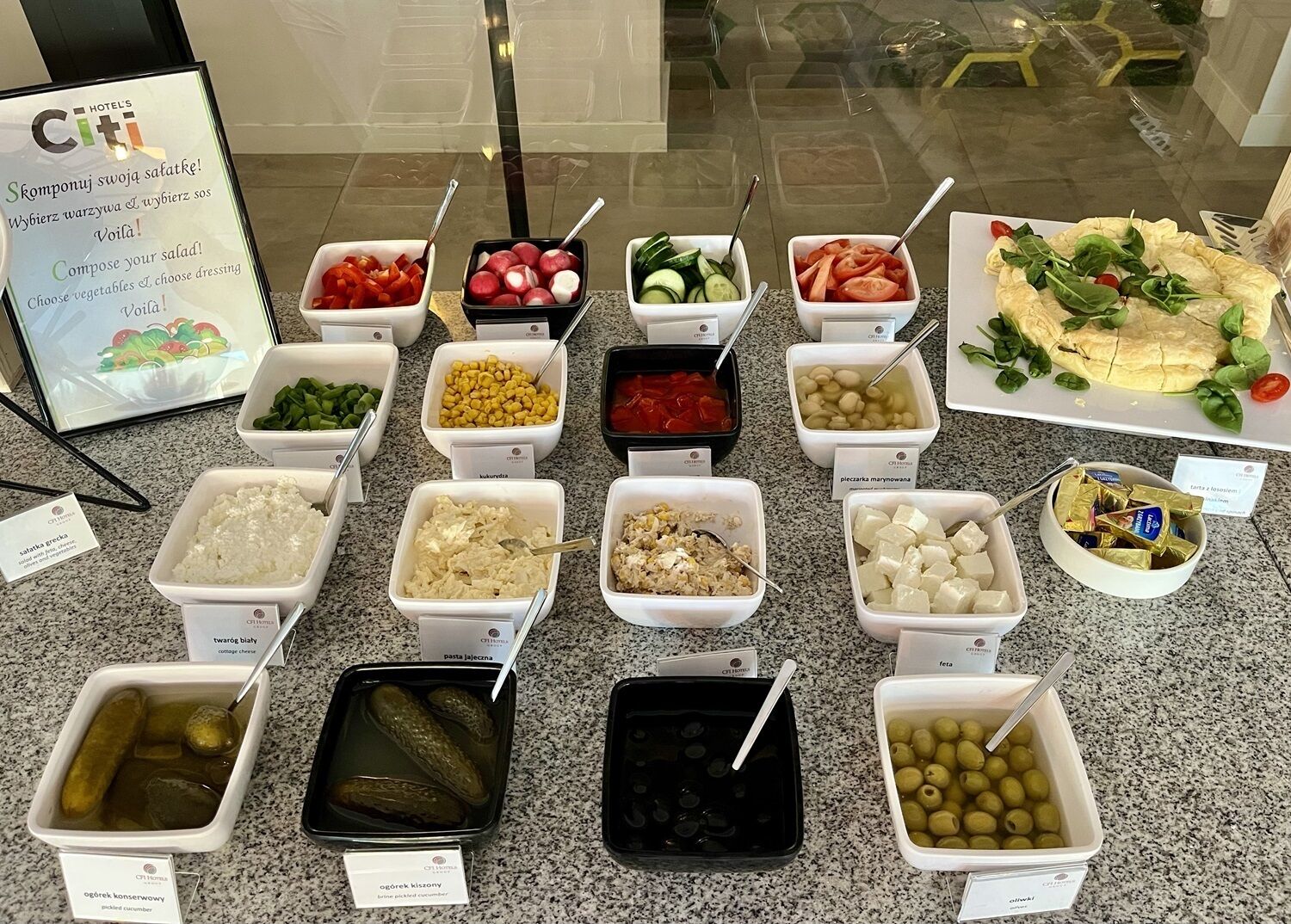 Buffet abundant amb diverses opcions de menjar, incloses amanides, formatges i aliments envinagrats.