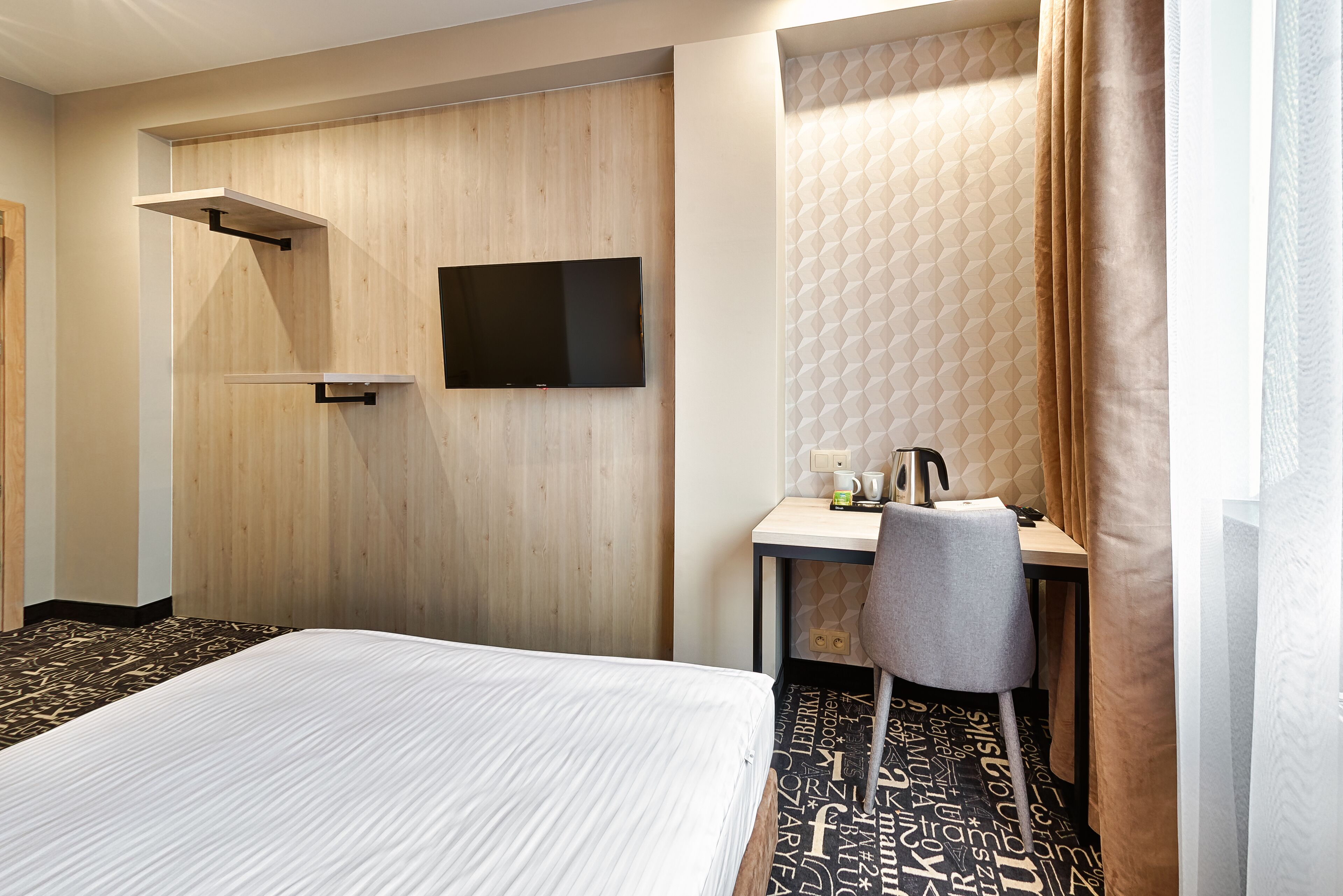 Ein Hotelzimmer mit Bett, Schreibtisch, Stuhl, Fernseher und Duschbereich.