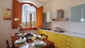 Una cucina con mobili gialli, un piano di lavoro bianco e una finestra con tende.