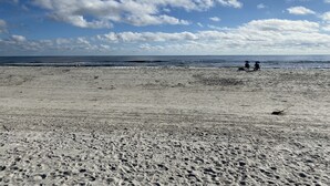 A beach with footprints and a few people walking. - 2 min walk to the beach from our Ocean Escape Jax Beach 3BR home! (Jacksonville Beach)
