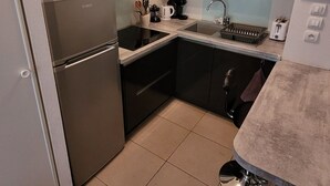 Une cuisine compacte équipée d’un réfrigérateur, d’un four à micro-ondes, d’un évier et d’un petit plan de travail.