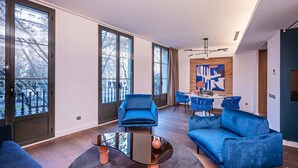 Una sala de estar moderna con ventanas amplias, un comedor y un sofá azul.