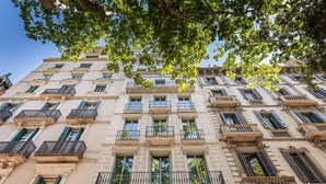 Un edificio de varios pisos con balcones, ventanas amplias y detalles arquitectónicos de estilo clásico.