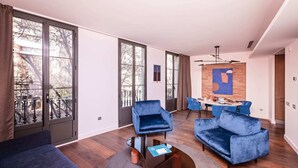 Ein modernes Wohnzimmer mit großen Fenstern, einem Essbereich mit blauen Stühlen und einem blauen Sofa.
