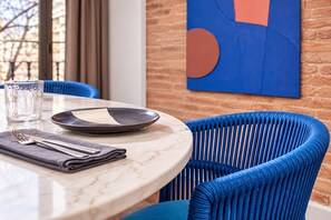 A dining table with a plate, cutlery, and a glass. Blue chairs surround the table.