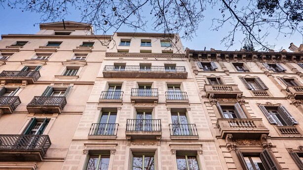 Ein mehrgeschossiges Gebäude mit Balkonen, großen Fenstern und klassischen architektonischen Details.