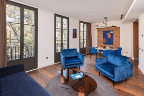 Ein modernes Wohnzimmer mit einem blauen Sofa, einem Glastisch und einem Essbereich mit blauen Stühlen.