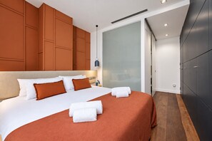 Ein modernes Hotelzimmer mit einem großen Bett, einem Schiebetürenschrank und Blick auf die Stadt.