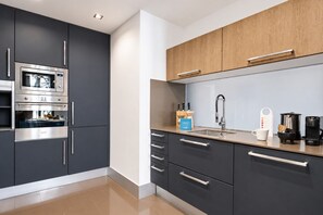 Eine moderne Küche mit dunklen Schränken, Edelstahlgeräten und einer Holz Arbeitsplatte.