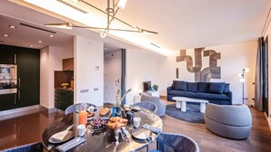 Una sala de estar moderna con comedor, que presenta una mesa redonda grande preparada para el desayuno, un sofá y un televisor.