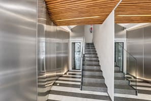 Een modern interieur met een trap, metalen wanden en een houten plafond.