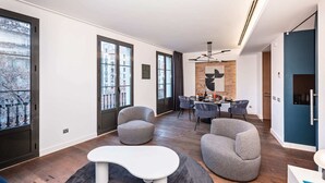 Un salon moderne avec un coin repas, de grandes fenêtres et une vue sur le paysage urbain.