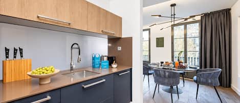 Una cocina moderna con un lavamanos, armarios y un comedor con mesa y sillas.