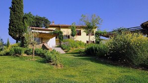 A house with a garden, a large tree, and a clear blue sky.