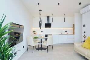 A modern kitchen with white cabinets, a black range hood, and pendant lighting. - Hedera Estate, Hedera A28 (Dubrovnik)
