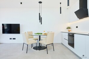 Una cocina moderna con una mesa de comedor, sillas, un televisor y un horno empotrado.